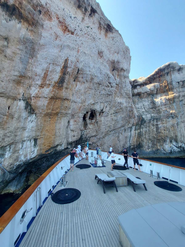 People on a ship in front of a rock wall on Kornati during a cruise  of the Croatia cost