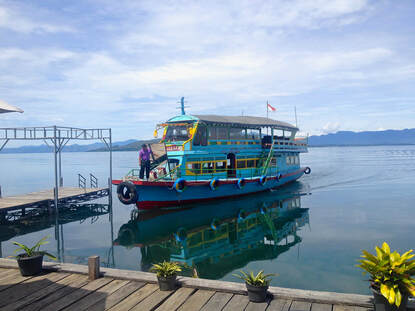 On a lake in Sumatra, a blue boat is about to dock 